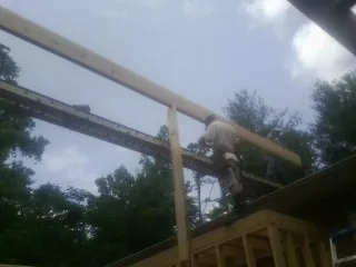 Carpenter setting a ridge beam over a new addition frame — Ice Dam Removal by Roofing Brothers in Palatka