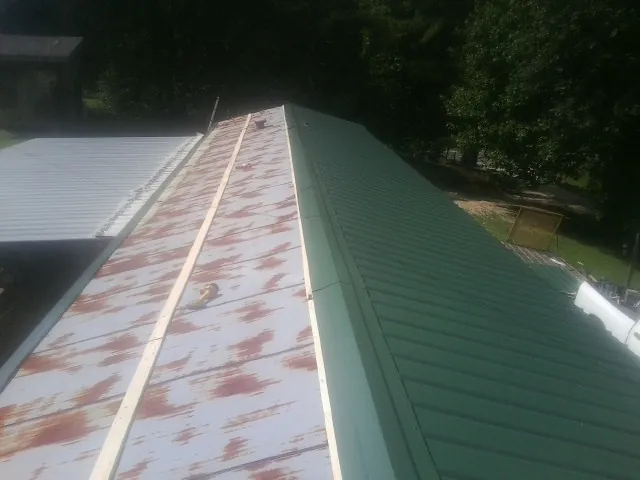 Old rusted panels beside newly installed green metal roofing — Wind Damage Roof Repair by Roofing Brothers in Palatka