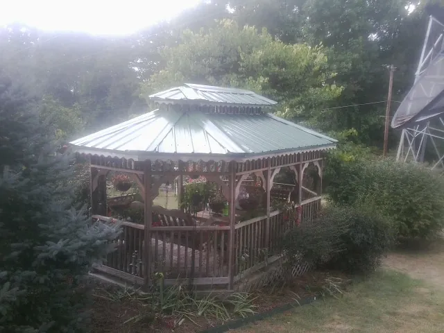Green metal roof on a backyard gazebo surrounded by garden beds in Palatka