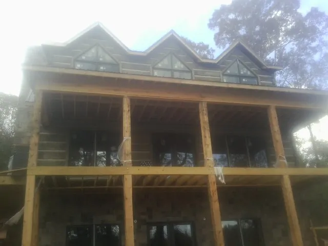 Dormers and porch framing on a large log home under construction — Roof Coating work by our crew in Palatka