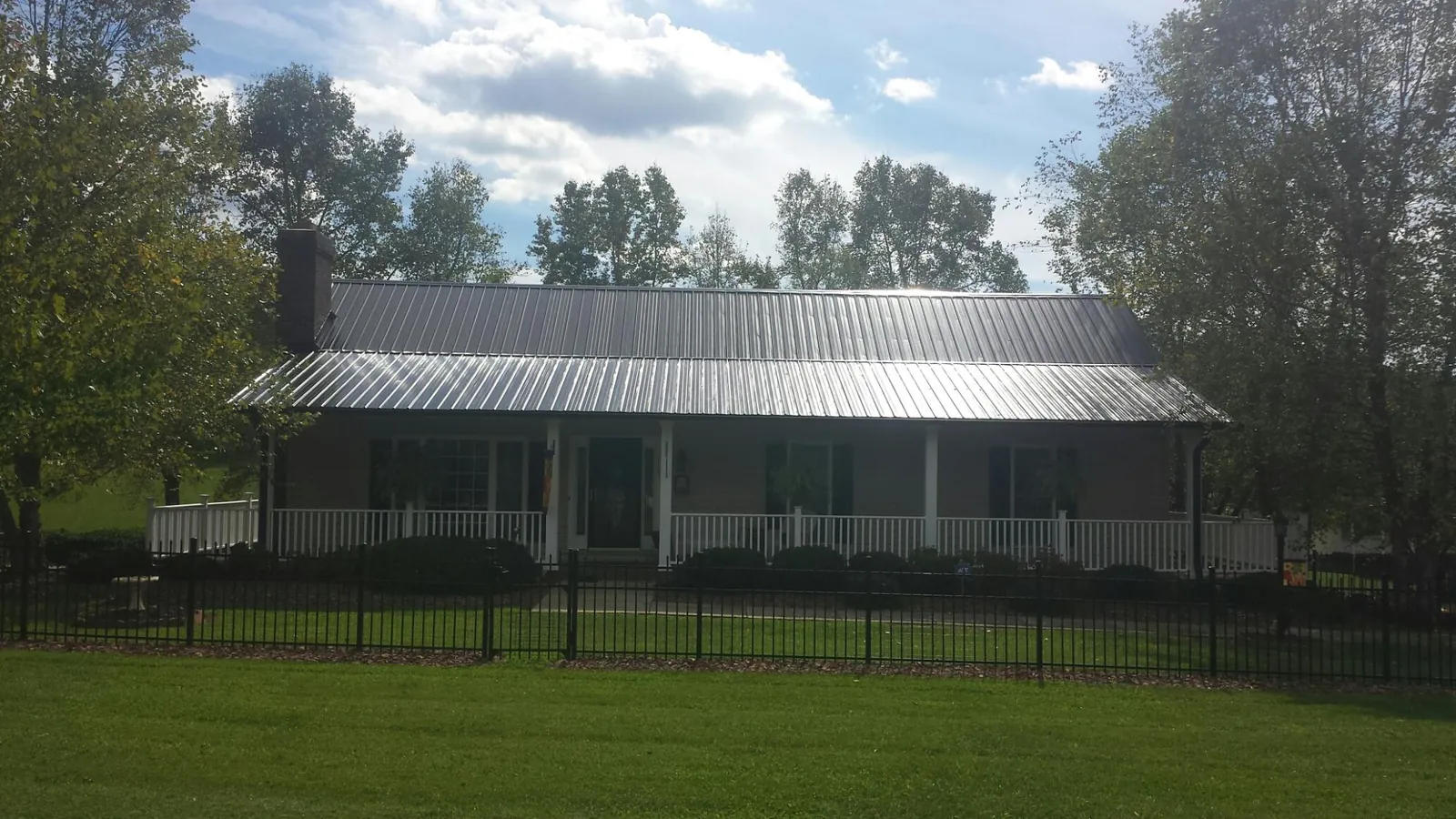 Gray metal roof on a brick ranch with a full width front porch — Gutter Guard Installation work by our crew in Palatka
