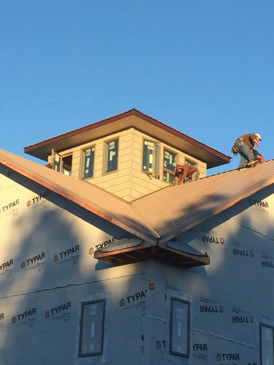 Roofers working around a rooftop cupola on a new metal roof at sunset — Roof Waterproofing in Palatka by Roofing Brothers